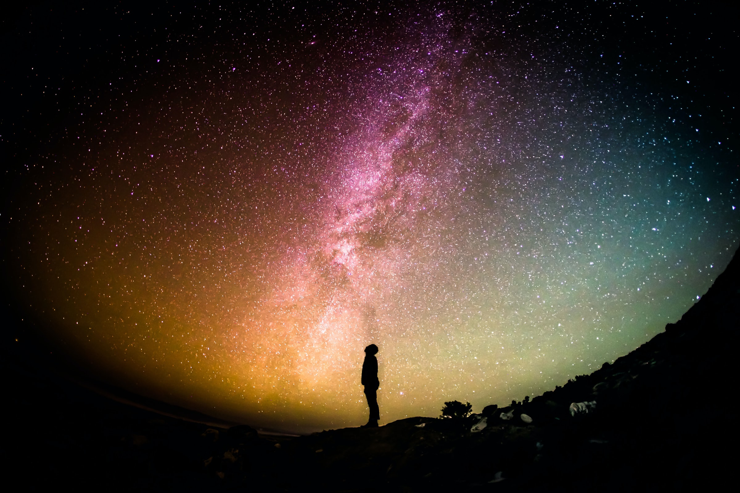 person looking up at a colorful sky full of stars