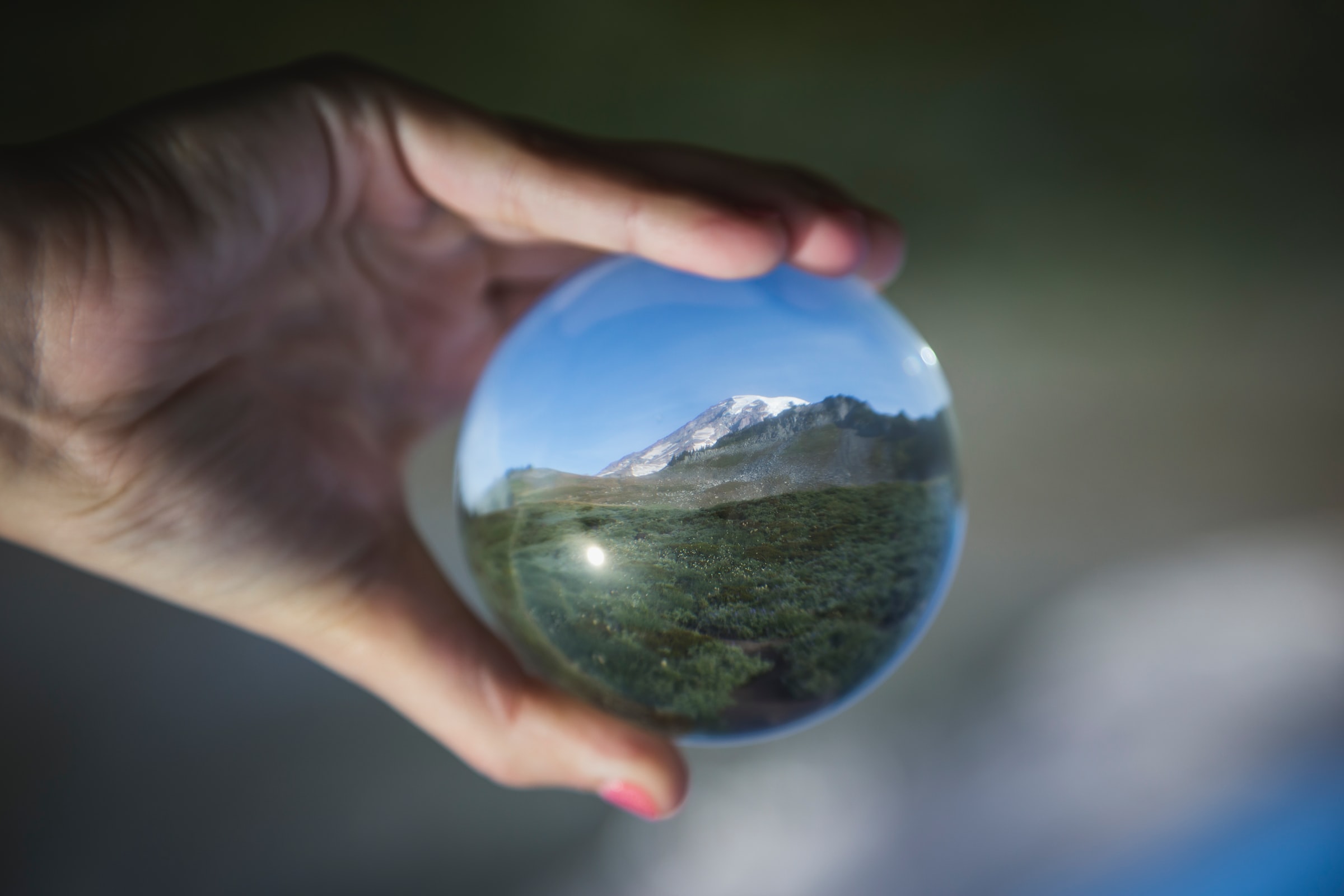 hand holding glass orb with a mountain inside of it